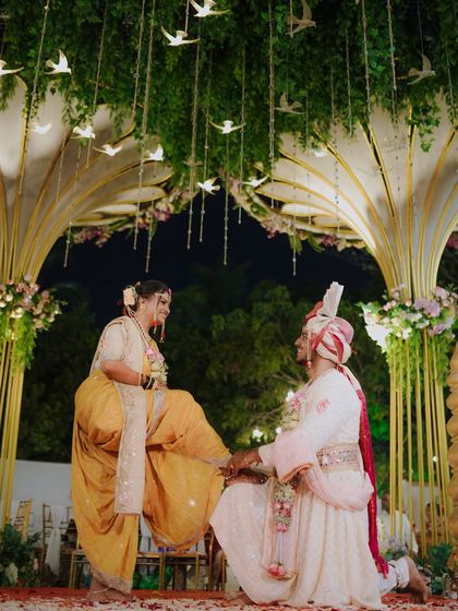 A playful and traditional moment where the bride, dressed in a stunning 'nauvari', asserts her presence. This shot, set against a beautifully decorated mandap, is full of cultural charm.