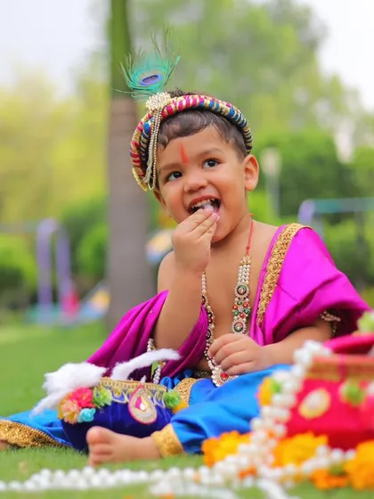 Capturing the playful spirit of Janmashtami. This little boy looks adorable in his custom Krishna outfit, complete with a peacock feather crown and traditional jewelry.