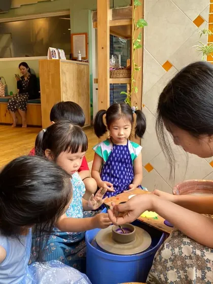A group of toddlers gathered around the pottery wheel. It's never too early to introduce children to the joy of creating with their hands.