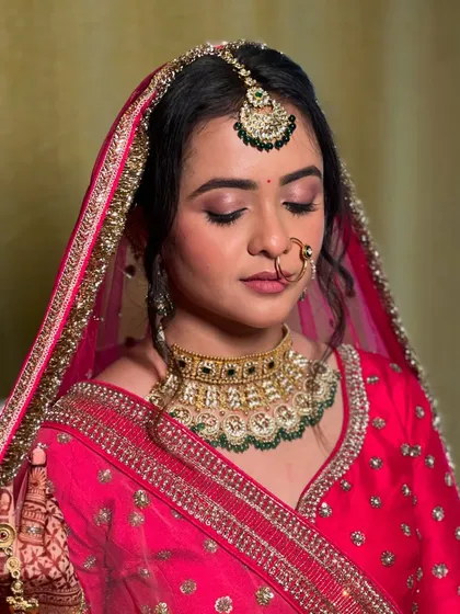 A close-up of the bridal makeup, featuring soft pink eyeshadow, a traditional nath, and a perfectly placed bindi.
