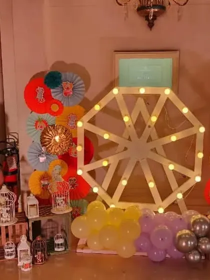 A decorative corner at a carnival party, featuring a light-up Ferris wheel and a lion cutout.