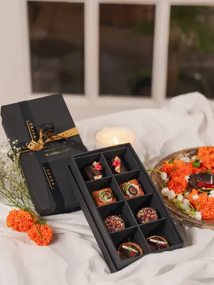 Celebrate Rakhi with our box of eight modern Indian sweet bites. Set against a festive backdrop with marigolds and a candle, this gift is perfect for a cozy, heartfelt celebration.