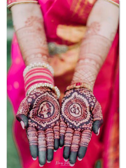 The rich, dark stain of a detailed engagement mehendi. This design features a portrait of the couple in one palm and interlocking rings in the other, surrounded by traditional patterns.