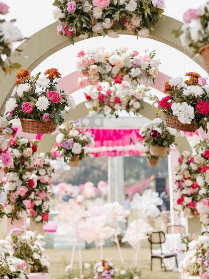 A detailed view of the floral arrangements on the pastel entrance arches in Goa. Wicker baskets filled with pink and white roses hang from the structure, adding a rustic and charming touch.