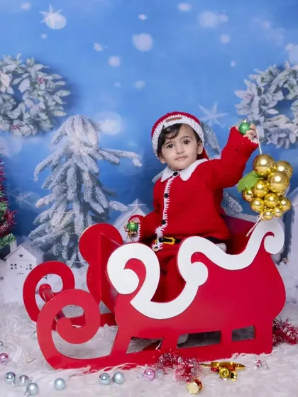 Another angle of the festive sleigh ride, this time with the baby holding a golden ornament. The variety of poses ensures you get a wide selection of beautiful holiday photos.