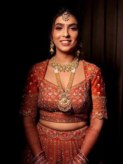 A close-up portrait of the bride. The makeup features a warm, bronzed eye look and a nude lip to balance the vibrant color of her outfit.