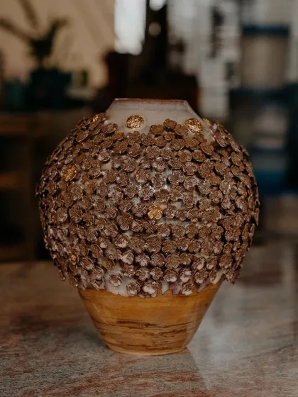 This is my 'Floral Grace' vase, a piece I am incredibly proud of. It is wheel-thrown and then adorned with hundreds of tiny, individually handcrafted clay flowers, with little touches of gold to catch the light.