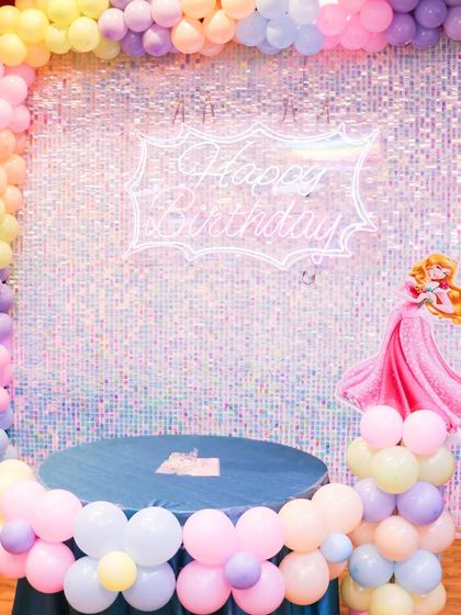 A classic princess theme setup featuring a Sleeping Beauty character. The pastel balloon decorations and shimmering backdrop create a dreamy atmosphere for a royal birthday ball.