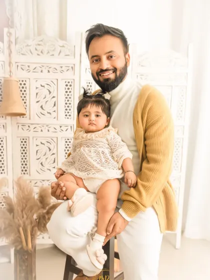 A proud father holds his baby daughter, both looking at the camera for a lovely father-daughter portrait.