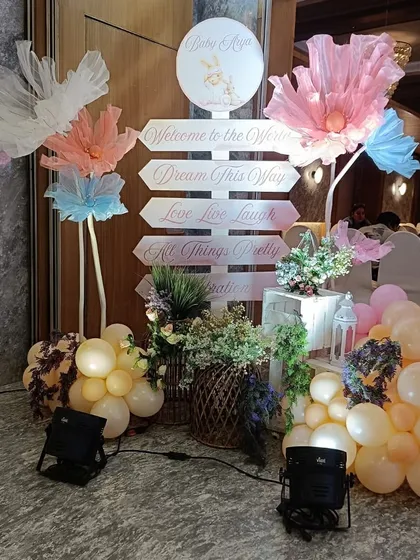 A whimsical welcome signpost for a bunny-themed party, with directions to "Dream This Way" and "All Things Pretty," surrounded by floral and balloon decor.