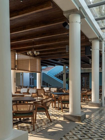 Inside the colonnade, the space is designed for comfortable lounging and dining. The use of Sadharhalli stone for the columns and a skylight separating the new from the old are details that honor the site's legacy.