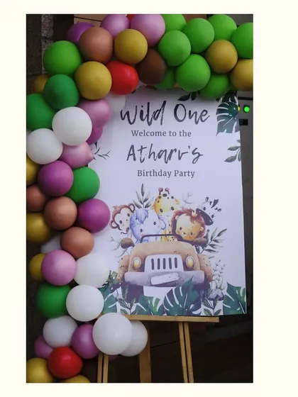 The welcome sign for Atharv's jungle party, framed by a balloon garland in a mix of bright and earthy tones.