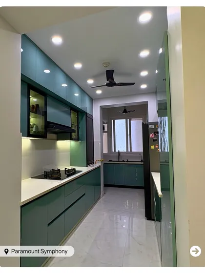 A long galley kitchen designed in a striking teal color. The layout maximizes counter space and storage, while recessed ceiling lights ensure a bright and efficient workspace.