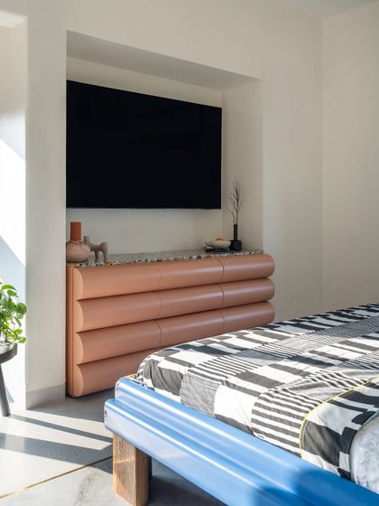 Functionality meets sculptural design in this bedroom detail. The custom-made drawers feature a unique, rounded form and are finished in a soft pink leather, providing stylish storage beneath the television.