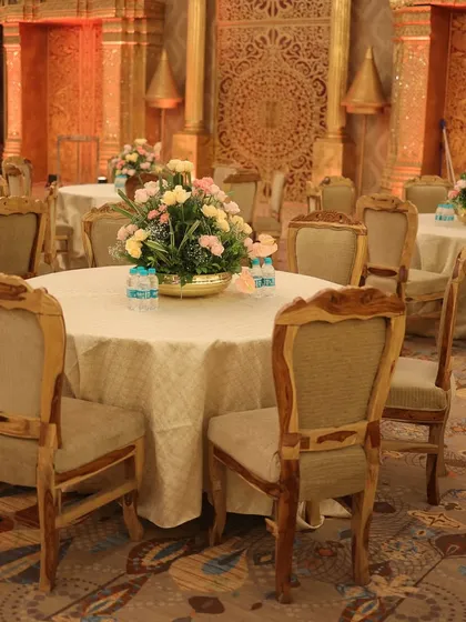 An elegant dining setup with wooden chairs and tables dressed in simple, off-white linens, allowing the floral centerpieces to shine.