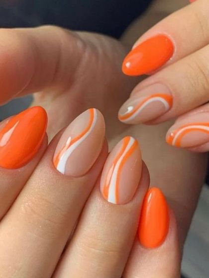 A bold orange manicure with abstract white swirls on the accent nails. This design combines a solid color with artistic flair for a balanced look.
