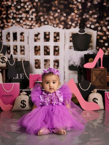 This little fashionista is ready for her close-up in a 'Miss Congeniality' inspired shoot. Dressed in a purple tulle dress, she's surrounded by glamorous props like shopping bags, high heels, and jewelry.
