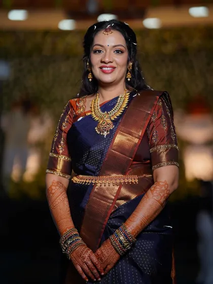 A full portrait from the engagement. The makeup complements her deep blue saree and traditional gold jewelry, creating a cohesive and elegant bridal look.