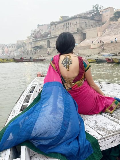 Sitting on a boat, looking out at the ghats of Varanasi. The tattoo on my back is a Sri Yantra, a sacred symbol of cosmic unity.