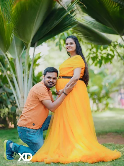 A happy and bright portrait, with the father-to-be looking up with a smile as he kneels by the baby bump.