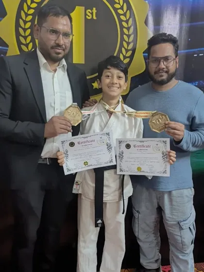 A young black belt student with his two gold medals and certificates, flanked by his proud coaches. This is the result of true dedication to the art of karate.