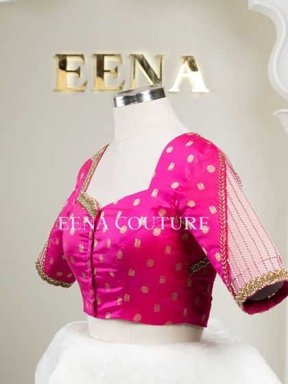 A closer look at the craftsmanship of this pink pure silk blouse. It features intricate handwork with bead detailing on the neckline and delicate net sleeves with linear embroidery for a touch of grace.