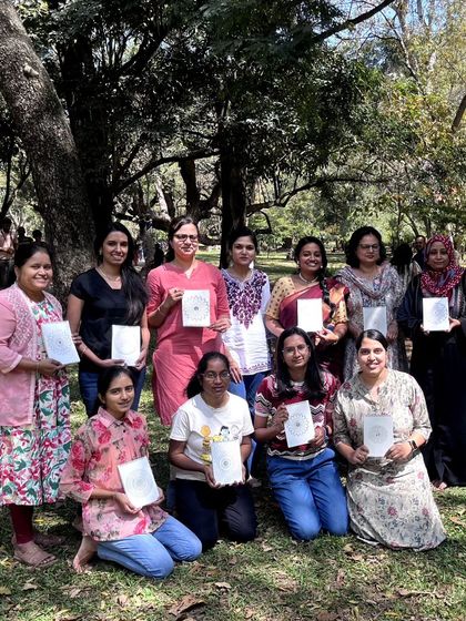 A group of participants proudly displays the dot mandala paintings they created during our "Strokes and Stories" session in the park. Everyone leaves with a finished piece of art and a smile.