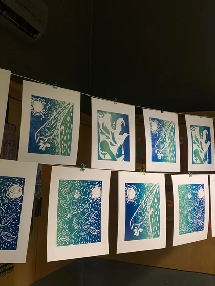 A beautiful series of two-color woodcut prints hanging to dry. This shows how a single carved block can be used to create a stunning edition of artworks.