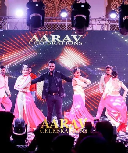 The energy is high during this sangeet performance. The dynamic choreography and colorful costumes of the backup dancers create a vibrant and exciting spectacle on stage.