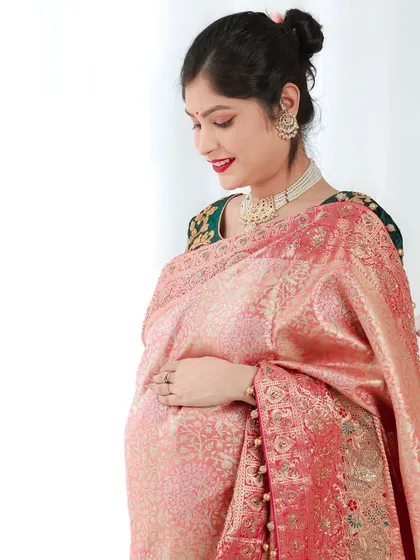 A quiet, contemplative pose in a traditional saree. This side profile beautifully highlights the baby bump and the elegant drape of the fabric.