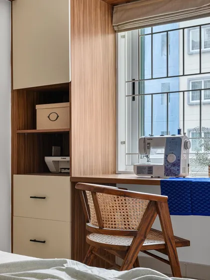 This dual-purpose space in the 'Poorna' guest bedroom serves as both a home office and a dedicated sewing station. The custom cabinetry provides organized storage for a printer and other supplies, right by the window.