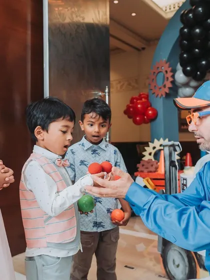 The children are fully engaged with the entertainer's magic tricks. Interactive entertainment is key to a successful kids' party.