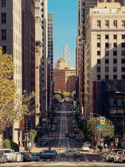 Looking down California Street in San Francisco, with the Bay Bridge framed in the distance. The compressed perspective from a telephoto lens emphasizes the city's famous hills.