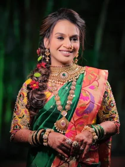 A smiling bride in a vibrant green Paithani saree, her hair adorned with flowers, and her hands featuring my detailed bridal mehendi.