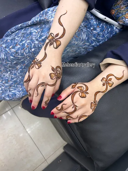 A playful and modern design featuring a trailing ribbon and bow pattern on both hands. This is a great example of how we can create fun and unconventional henna art.