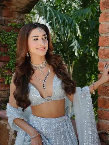 A close-up against a rustic brick wall. The contrast highlights the modern design of the blouse and the sparkle of the sequined lehenga I styled.