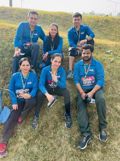 A group of runners relaxing on the grass after a challenging trail run, proudly wearing their medals.