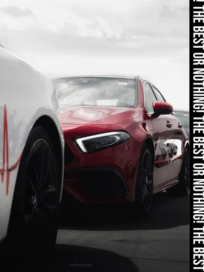A dynamic shot of a red Mercedes-AMG, partially obscured by another vehicle, creating a sense of anticipation and focusing on its aggressive front design. This image captures the brand's motto: "The best or nothing."