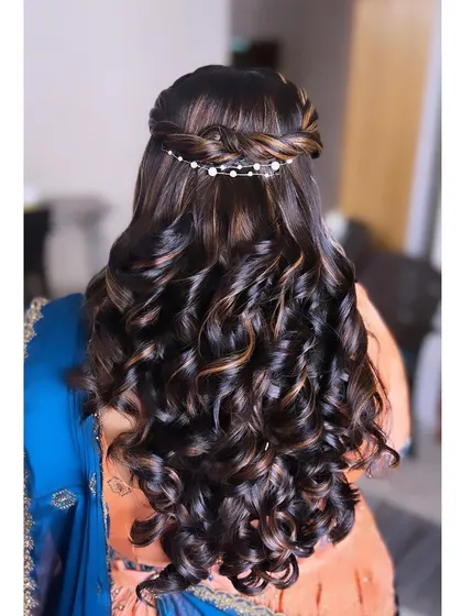 This half-up hairstyle features a waterfall braid and tight, defined curls, perfect for adding volume and texture. The subtle highlights in the hair are beautifully defined by the curls, creating a rich, dimensional look for any party.