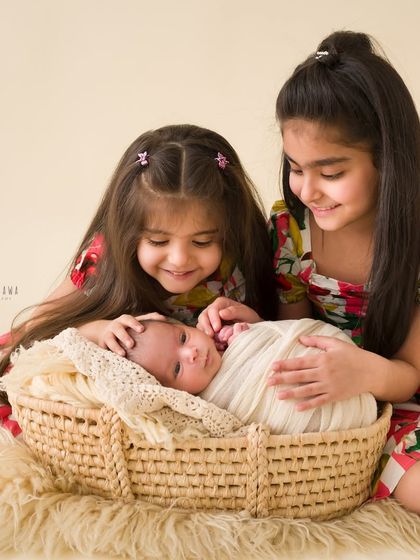 Big sisters doting on their new baby brother. This image is a heartwarming snapshot of sibling love from the very beginning.