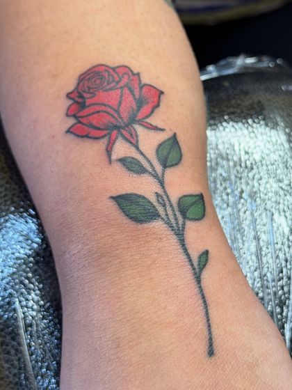 A close-up shot of the red rose tattoo, highlighting the shading and detail on the petals.