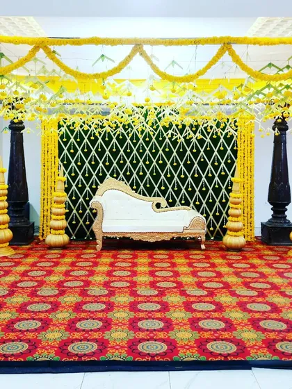 A traditional mantap setup with four pillars and a canopy of marigold garlands, ready for a ceremony.