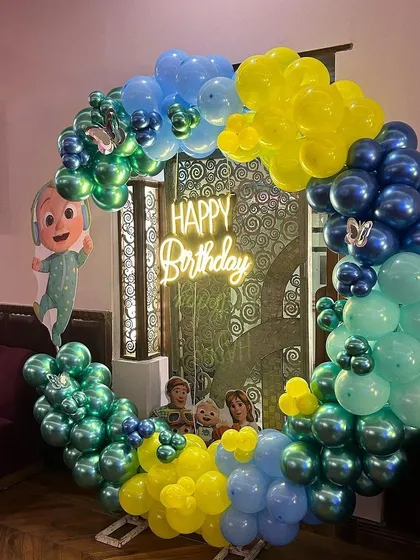 A creative Cocomelon balloon ring, perfect for photos. This setup uses a circular frame decorated with theme-colored balloons and character cutouts.