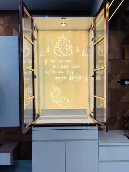 This is a custom-built pooja unit I designed, featuring fluted glass doors that conceal the sacred space when not in use. Opening the doors reveals a beautifully backlit panel with the Ganesh mantra, creating a serene and divine corner within the home.