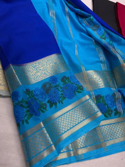A vibrant royal blue and sky blue semi-Mysore crepe saree with a matching floral border.