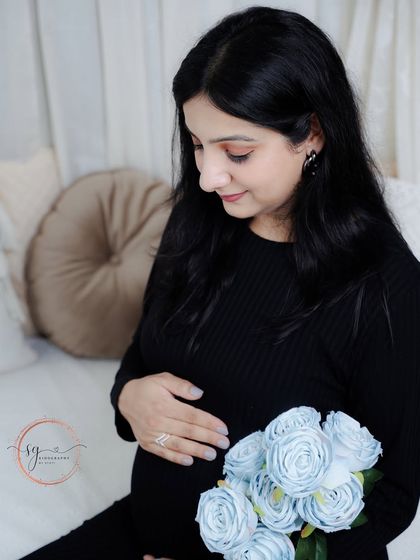 A close-up shot capturing a tender moment. The mom-to-be looks down at a bouquet of flowers, her expression soft and serene.