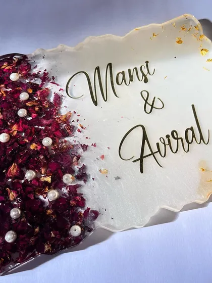 This 12x9 inch nameplate is a simple and elegant way to welcome guests to your home. It's made with preserved rose petals and pearls from a wedding garland.