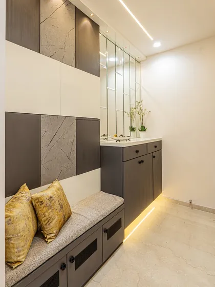 I designed this entryway with a built-in seating bench that doubles as shoe storage. The wall features a mix of textured panels, and the vertical mirrors make the space feel larger.