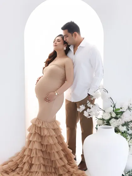 A portrait of quiet elegance and love. The neutral-toned ruffled gown is stunning against the minimalist white backdrop, focusing all attention on the couple's connection.