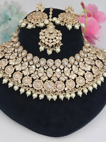 A beautiful champagne-gold Polki set with pearl accents, including a choker, earrings, and maang tikka.